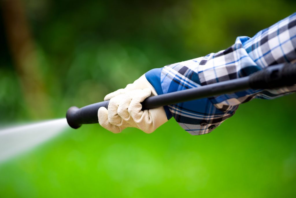 Gartenschlauch wird in Händen mit Handschuhen gehalten