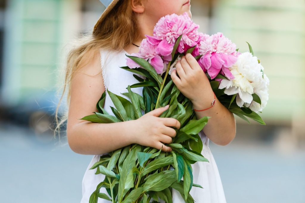 Kind mit Pfingstrosen in der Hand