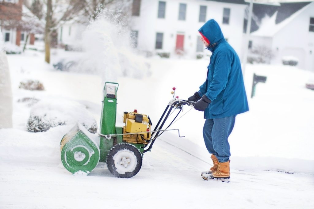 Mann mit Schneefräse im Schnee