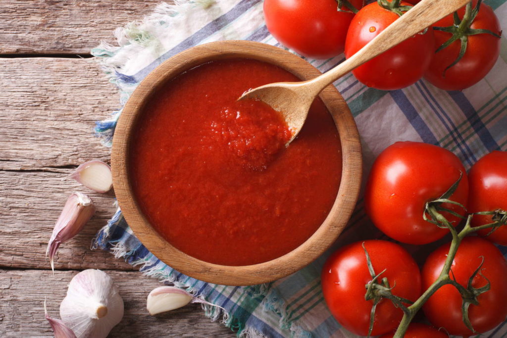 Tomatensoße in einer Holzschüssel mit frischen Tomaten