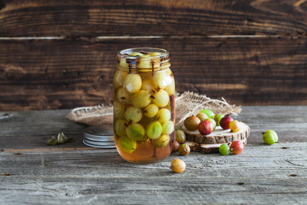 Stachelbeeren eingelegt im Marmeladenglas auf Holzhintergrund