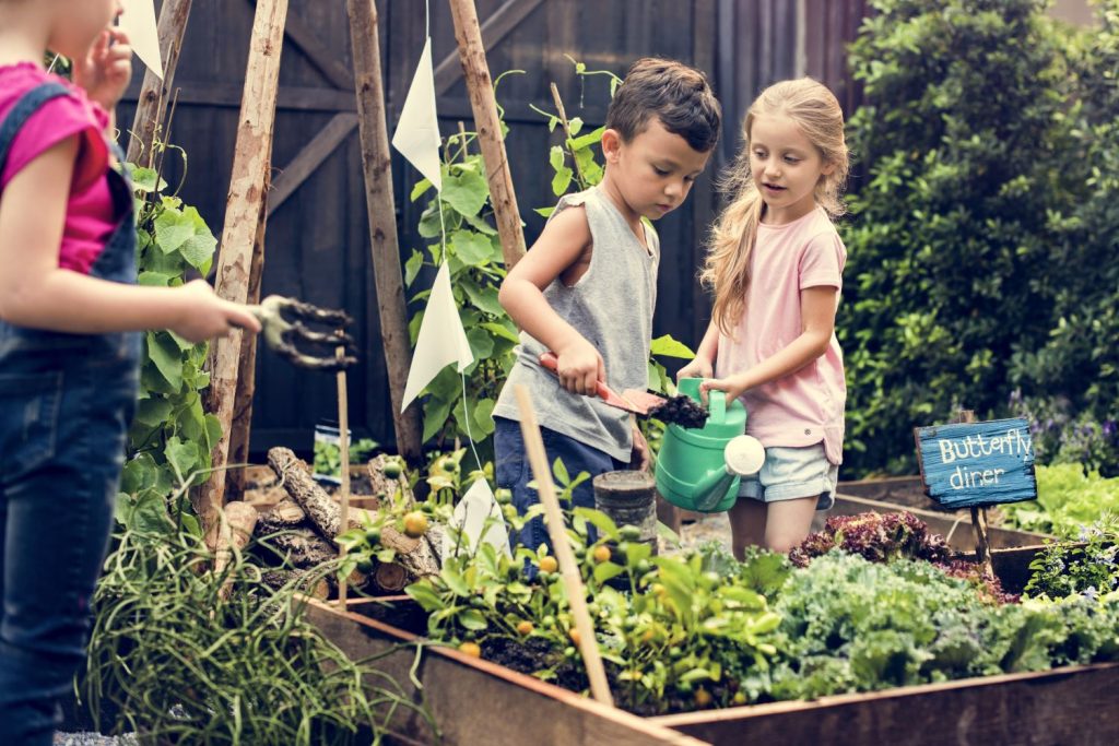 Kinder am Beet mit Gießkanne