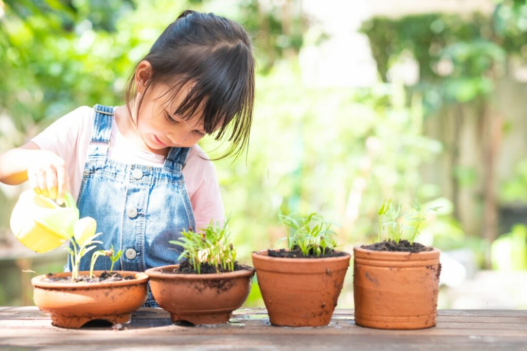 Kind gießt Pflanzen mit einer Gießkanne