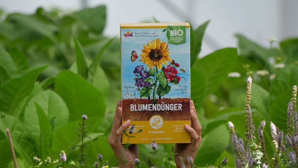 Plnatura Bio-Blumendünger wird hochgehalten