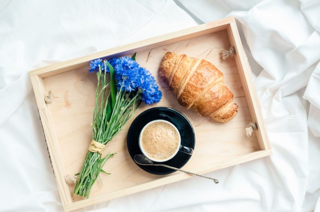 Kornblumen neben Croissant und Kaffee