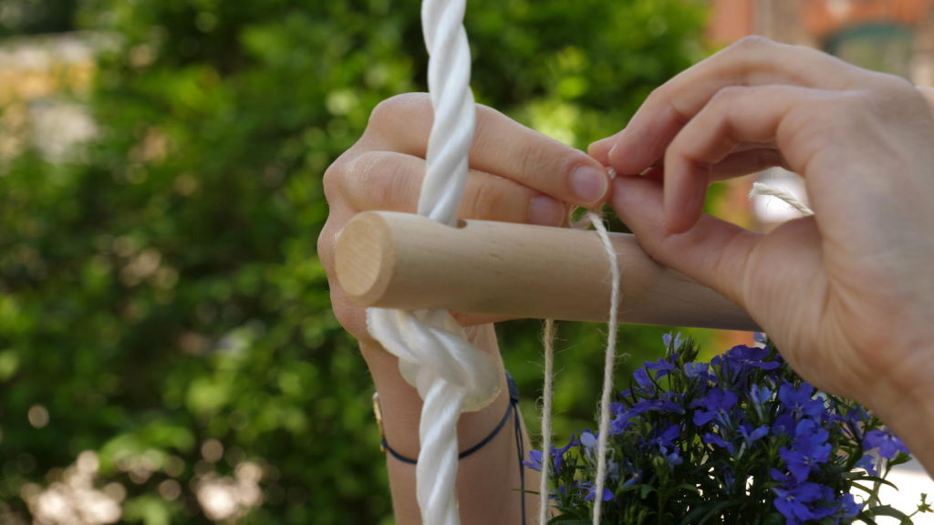 Blumentopf wird an einer Sprosse einer Strickleiter angebunden