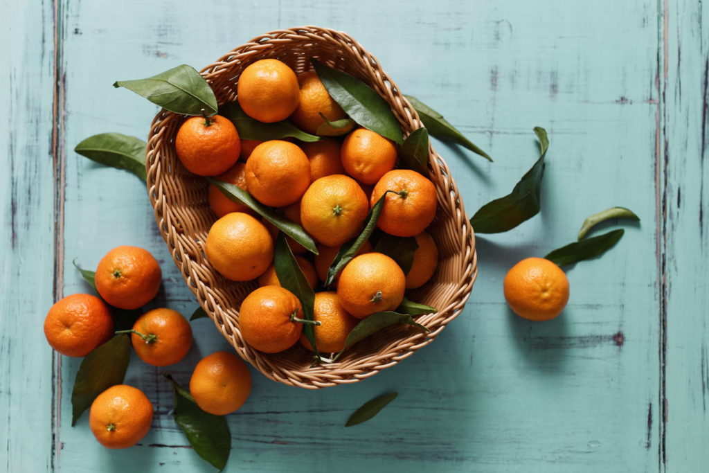 Mandarinen mit Blättern in Korb
