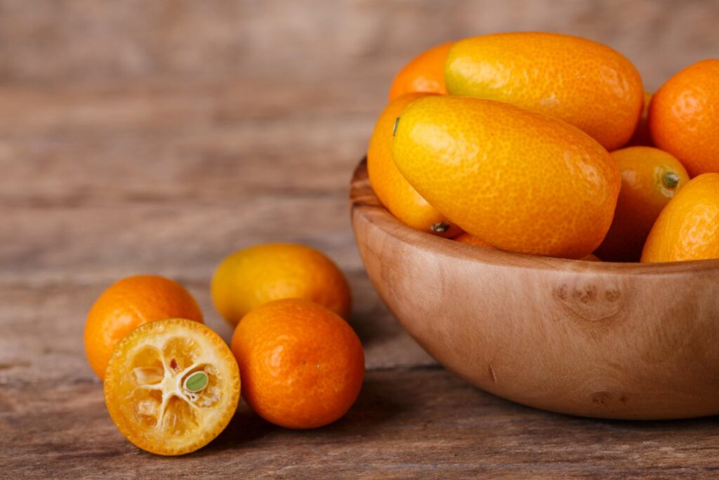 Aufgeschnittene Kumquat neben einer Schale Kumquats