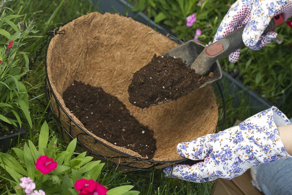Erde wird in einen Hängekorb für Blumen gefüllt